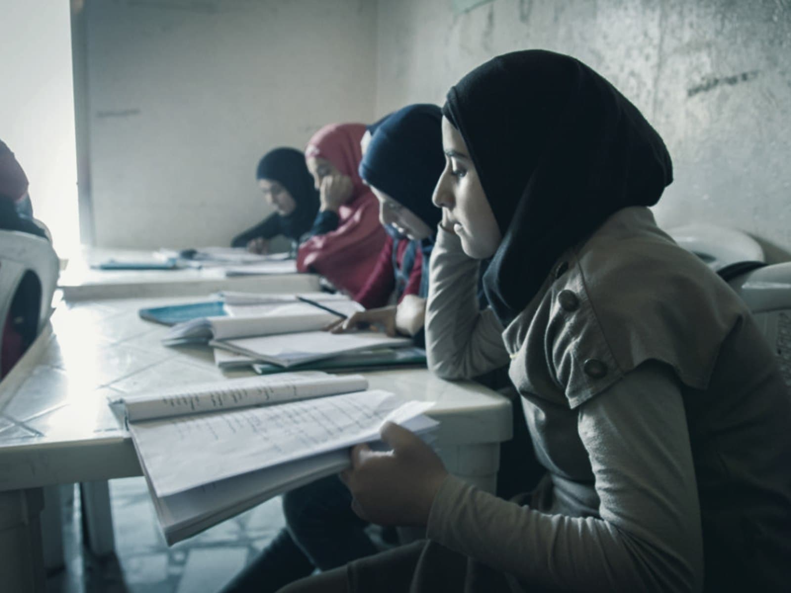 Students at a row of desks writing in exercise books